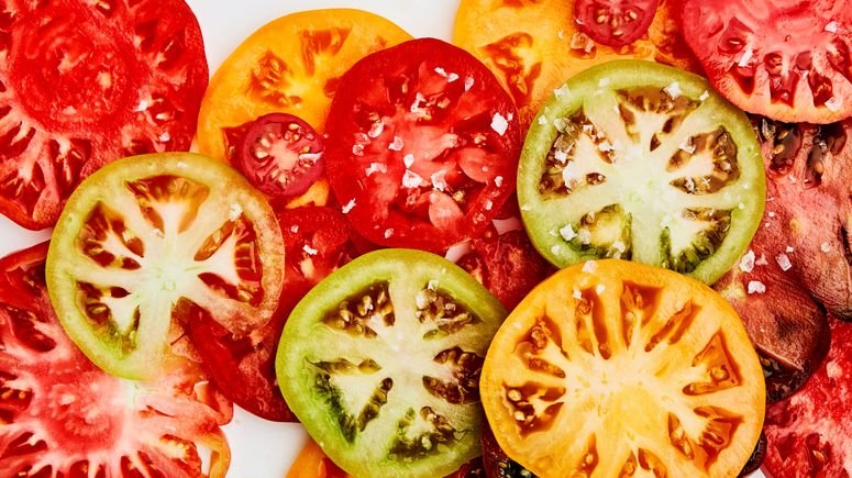 Sliced heirloom tomatoes in shades of red, yellow, green, and purple.