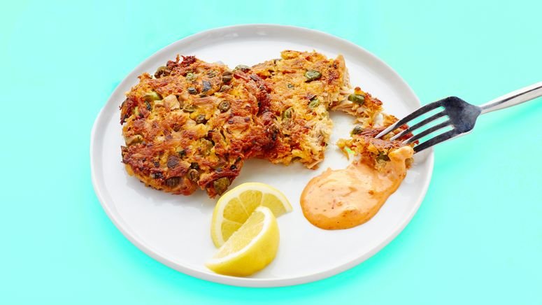 Crispy homemade tuna patties served on a white plate with spicy mayo dipping sauce and lemon wedges